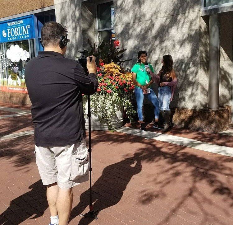 Brittaney Jenkins being interviewed by a woman outside a building, both being filmed by a camera man