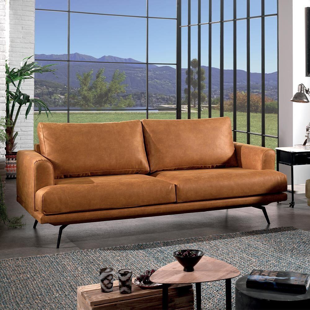 Canapé en cuir marron dans un salon moderne avec une grande fenêtre et vue sur la montagne.