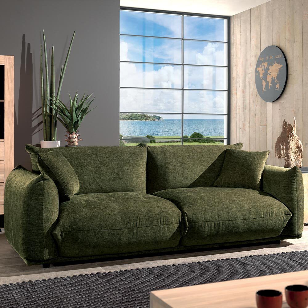 Canapé vert dans un salon avec une grande fenêtre et vue sur l'océan.