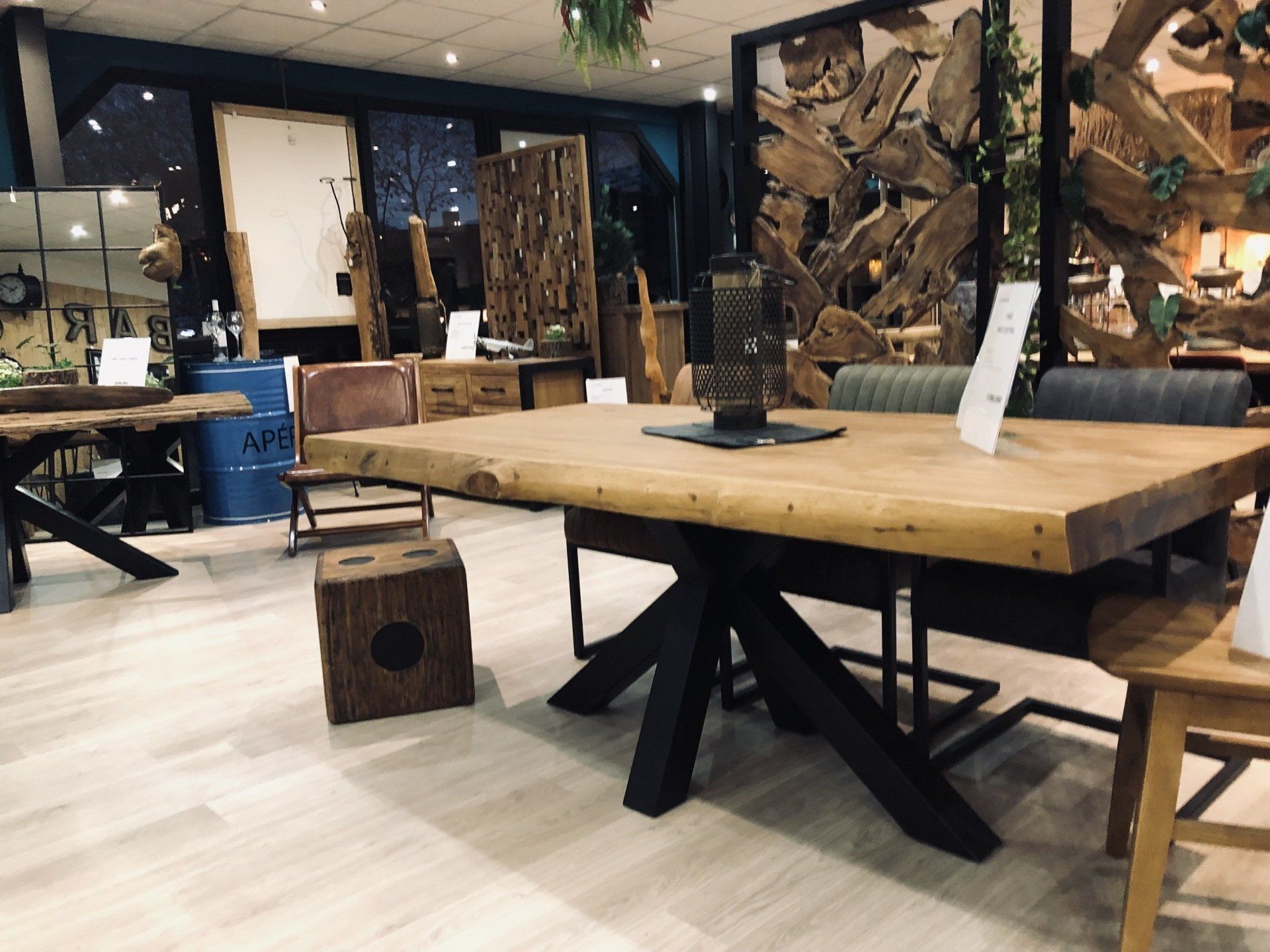 Présentation de meubles en bois dans une salle d'exposition, comprenant une grande table et des chaises.
