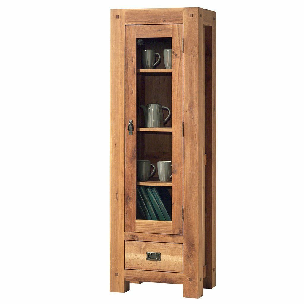 Haute armoire en bois avec porte vitrée, tiroir et étagères présentant des tasses et un livre.