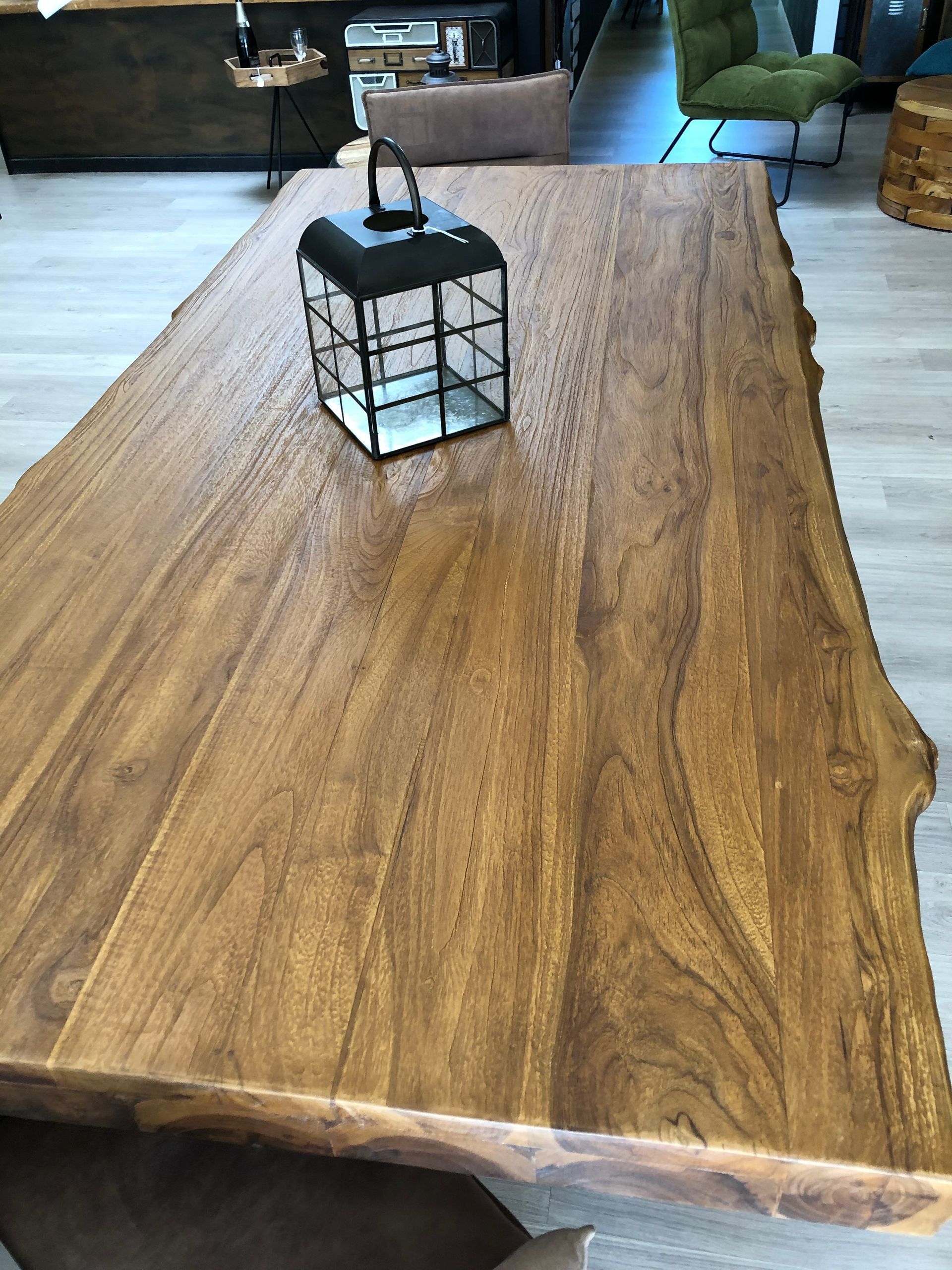 Présentation de meubles en bois dans une salle d'exposition, comprenant une grande table et des chaises.