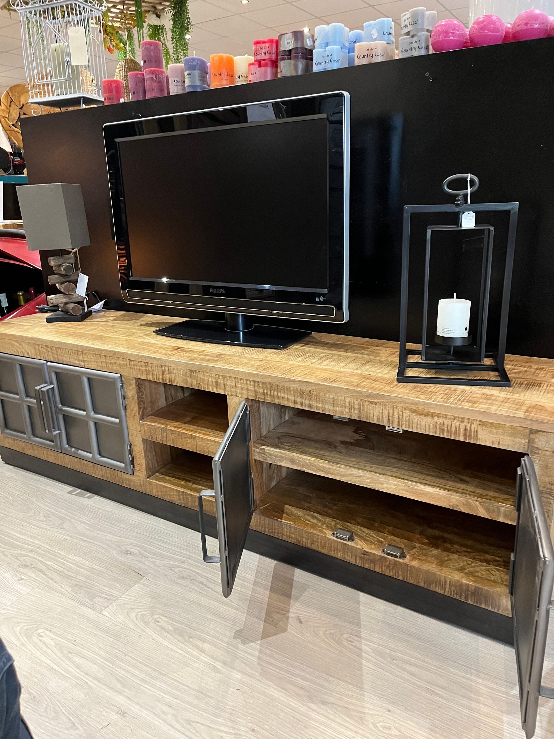 Un meuble TV en bois avec un téléviseur, des portes métalliques et des étagères.