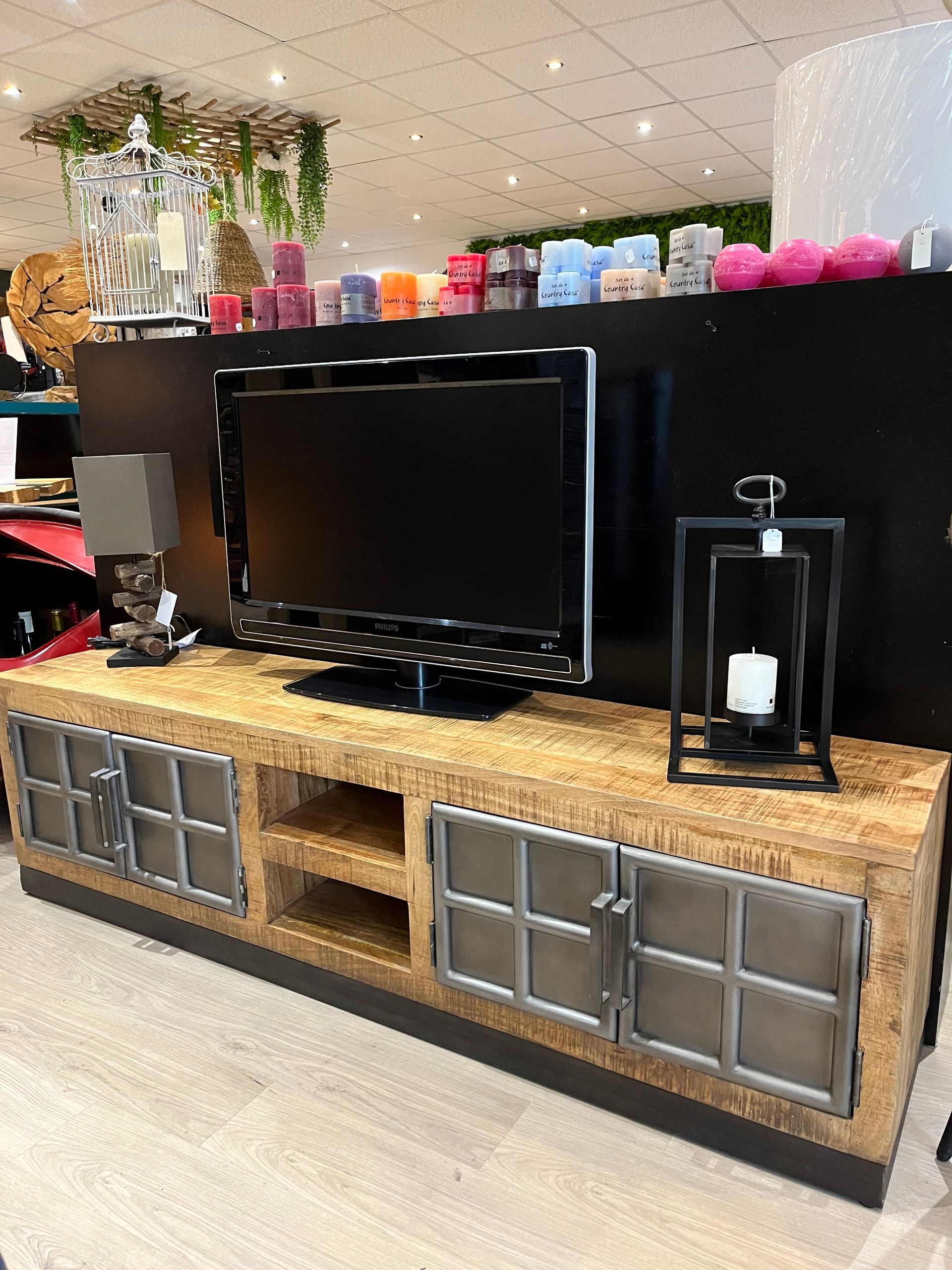 Un meuble TV en bois avec un téléviseur, des portes métalliques et des étagères.
