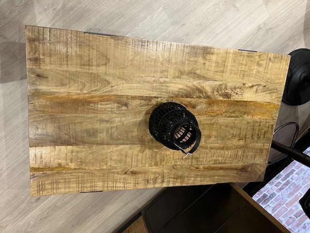 Table basse en bois avec pieds en métal noir ; vase décoratif noir sur le dessus.