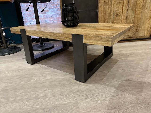 Table basse en bois avec pieds en métal noir ; vase décoratif noir sur le dessus.