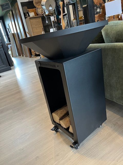 Brasero noir avec étagère de rangement contenant des bûches