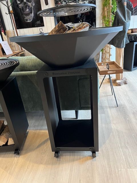 Cheminée d'extérieur noire sur pied avec étagère de rangement et roulettes. Aménagement intérieur.