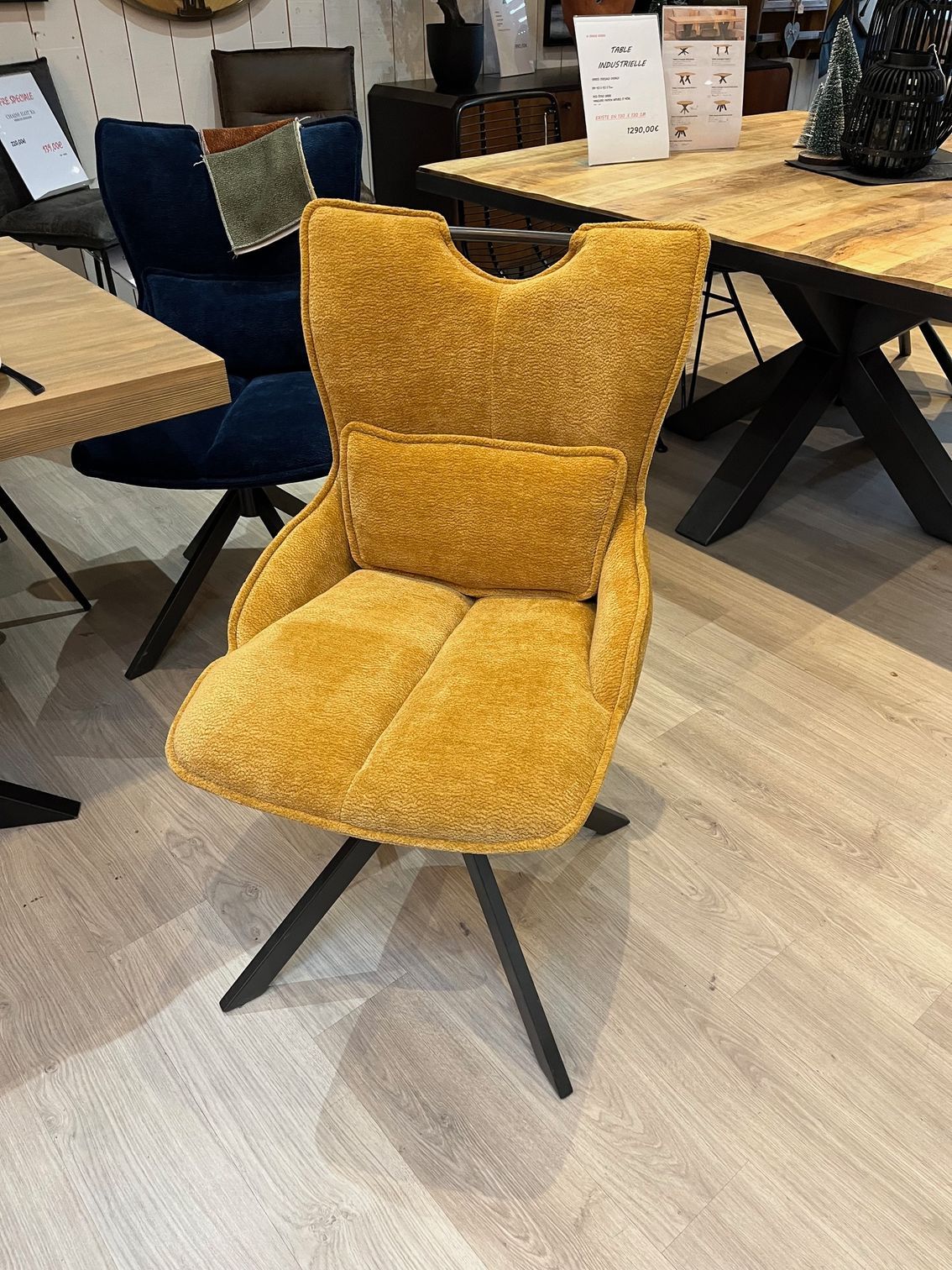 Fauteuil jaune rembourré avec coussin de dossier, sur pieds noirs.