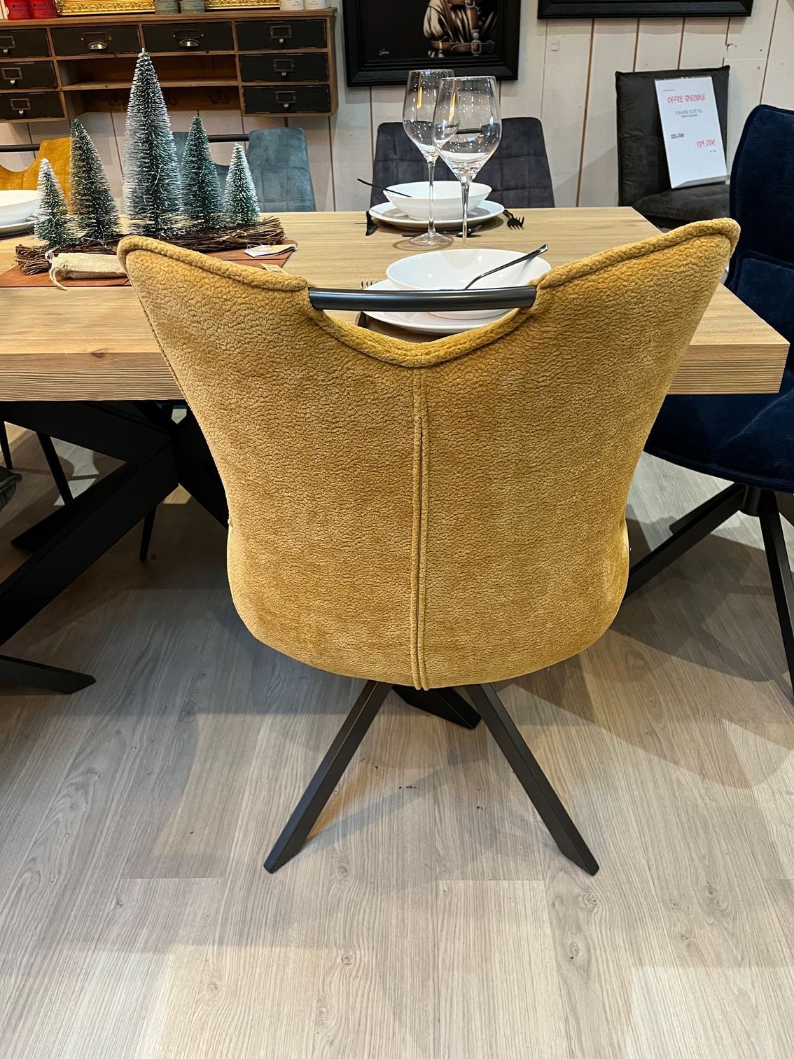 Fauteuil jaune rembourré avec coussin de dossier, sur pieds noirs.