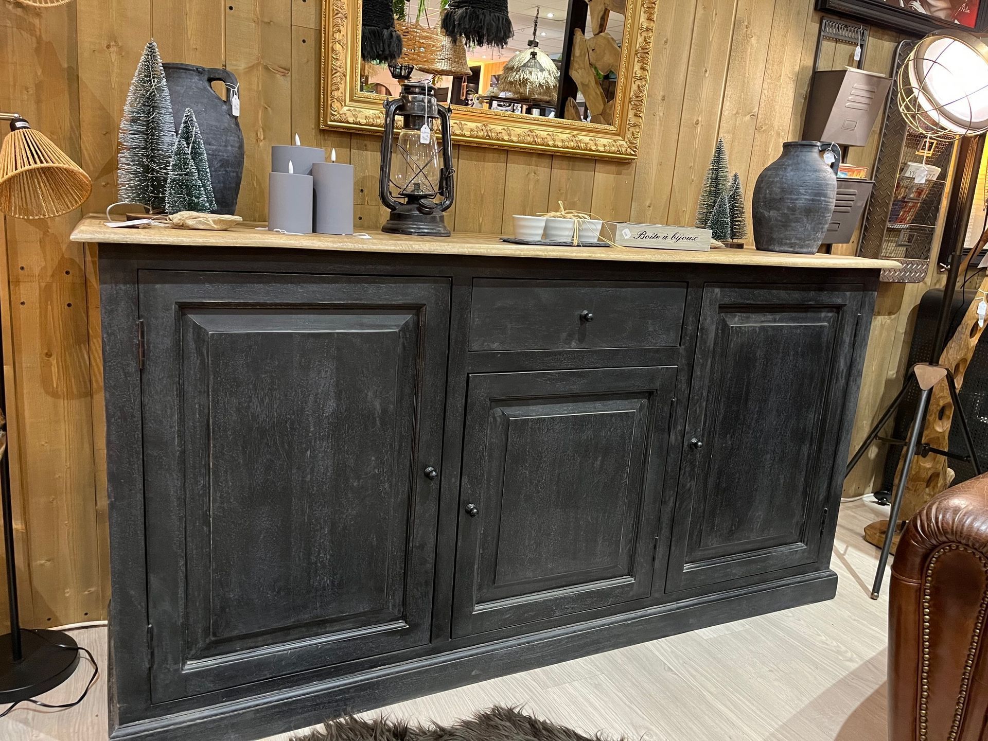 Meuble noir avec plateau en bois clair, décoré de bougies, de plantes et de vases.