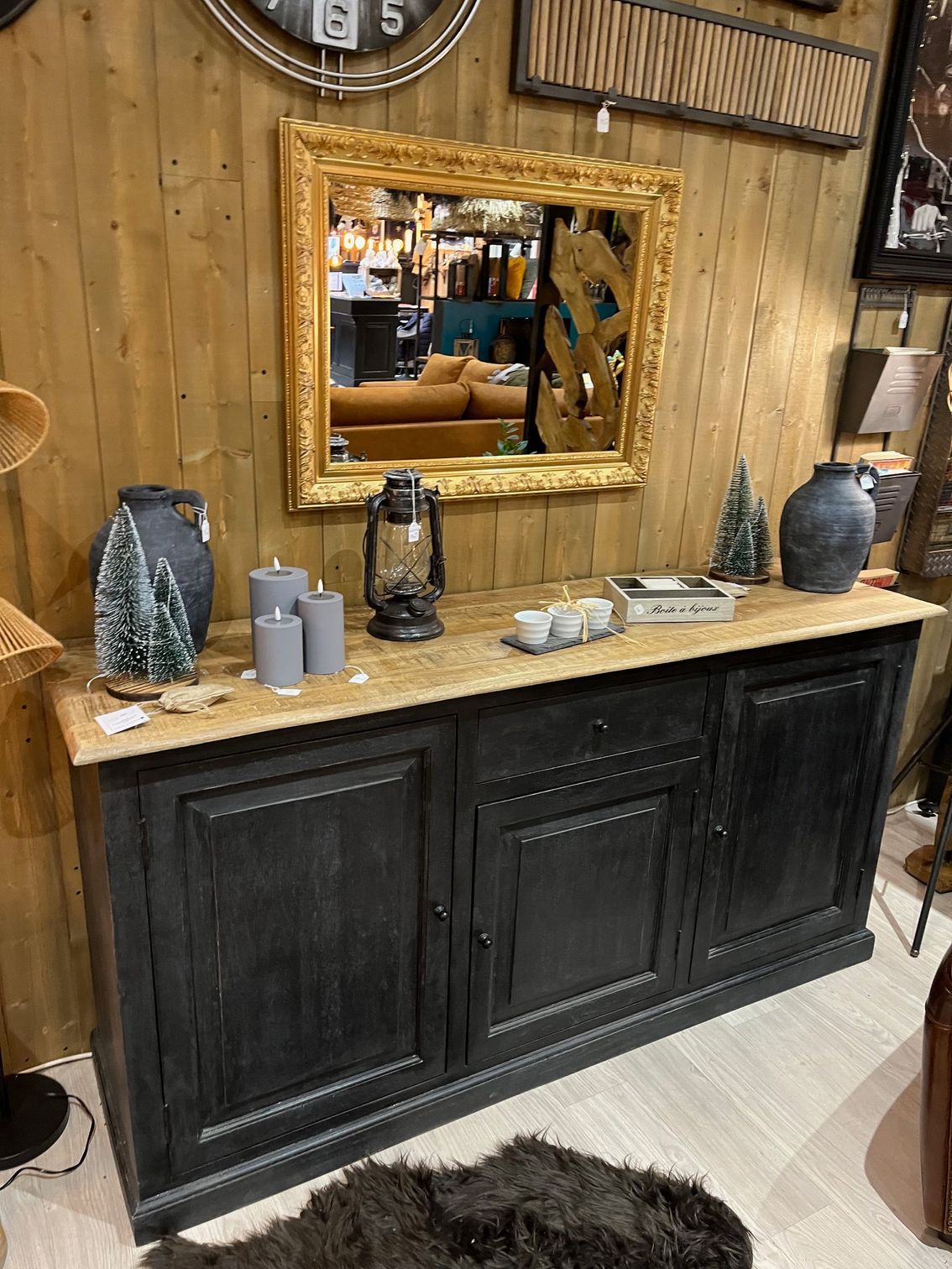 Meuble noir avec plateau en bois clair, décoré de bougies, de plantes et de vases.
