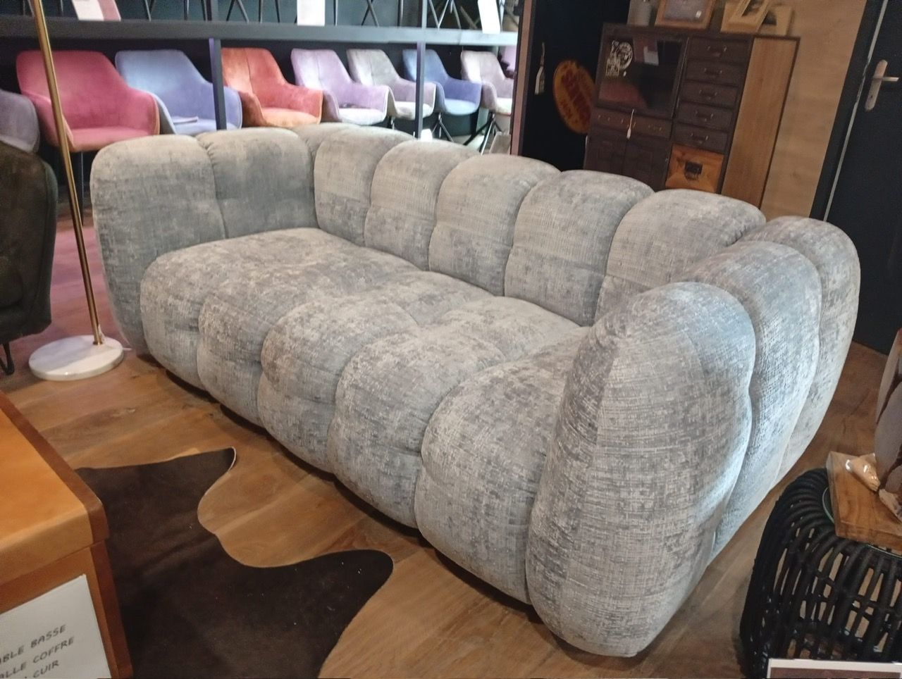Canapé capitonné marron dans un salon moderne avec une table basse ronde et un plafonnier décoratif.