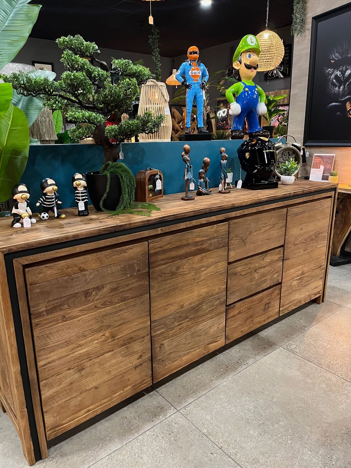 Vitrine en bois présentant de petites figurines et statues dans un décor évoquant un magasin