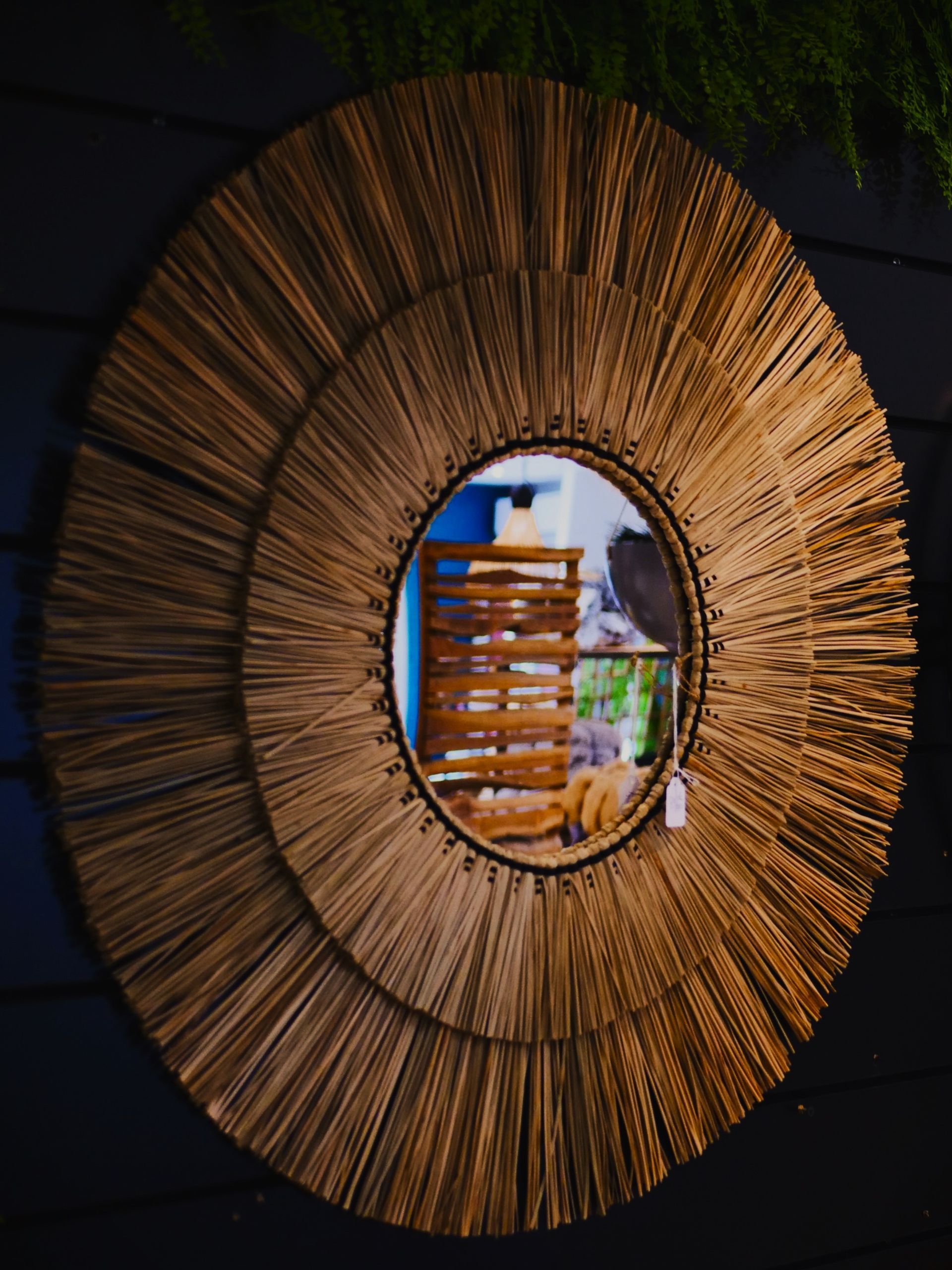 Miroir mural circulaire tissé avec des roseaux aux tons naturels rayonnant vers l'extérieur.