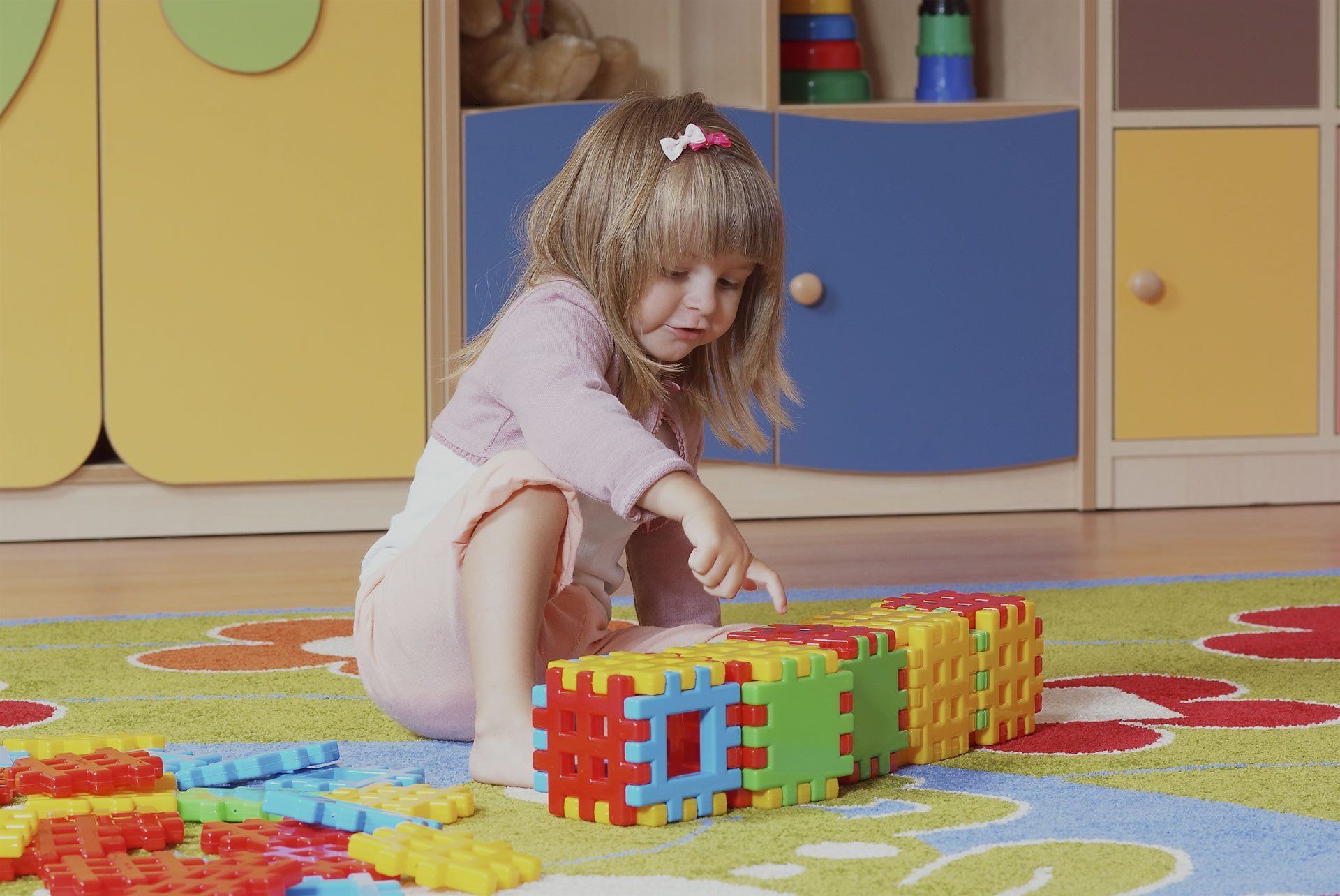 A child playing with toys on the floor of a preschool
