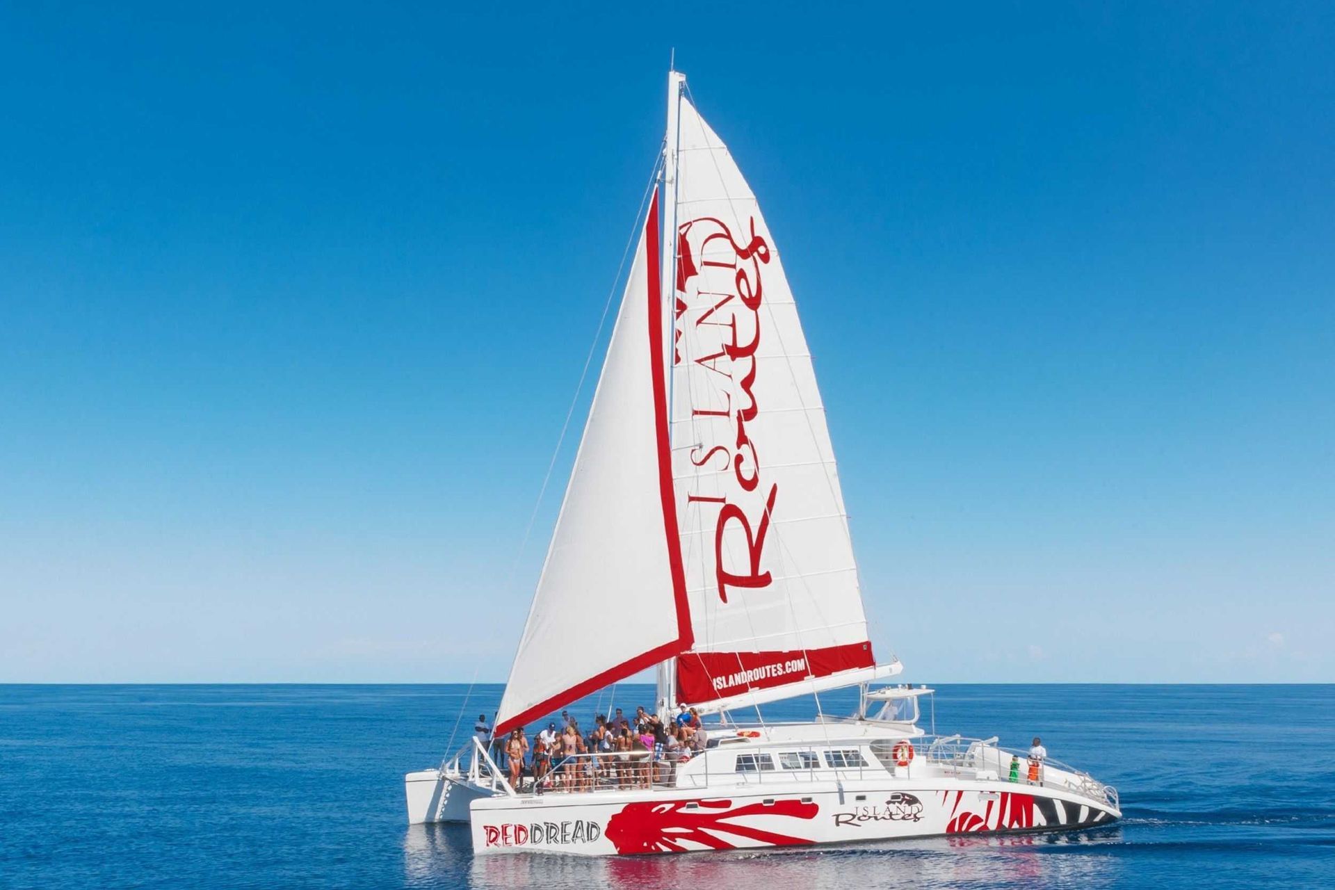 White sailboat with red accents on calm blue ocean under a clear sky