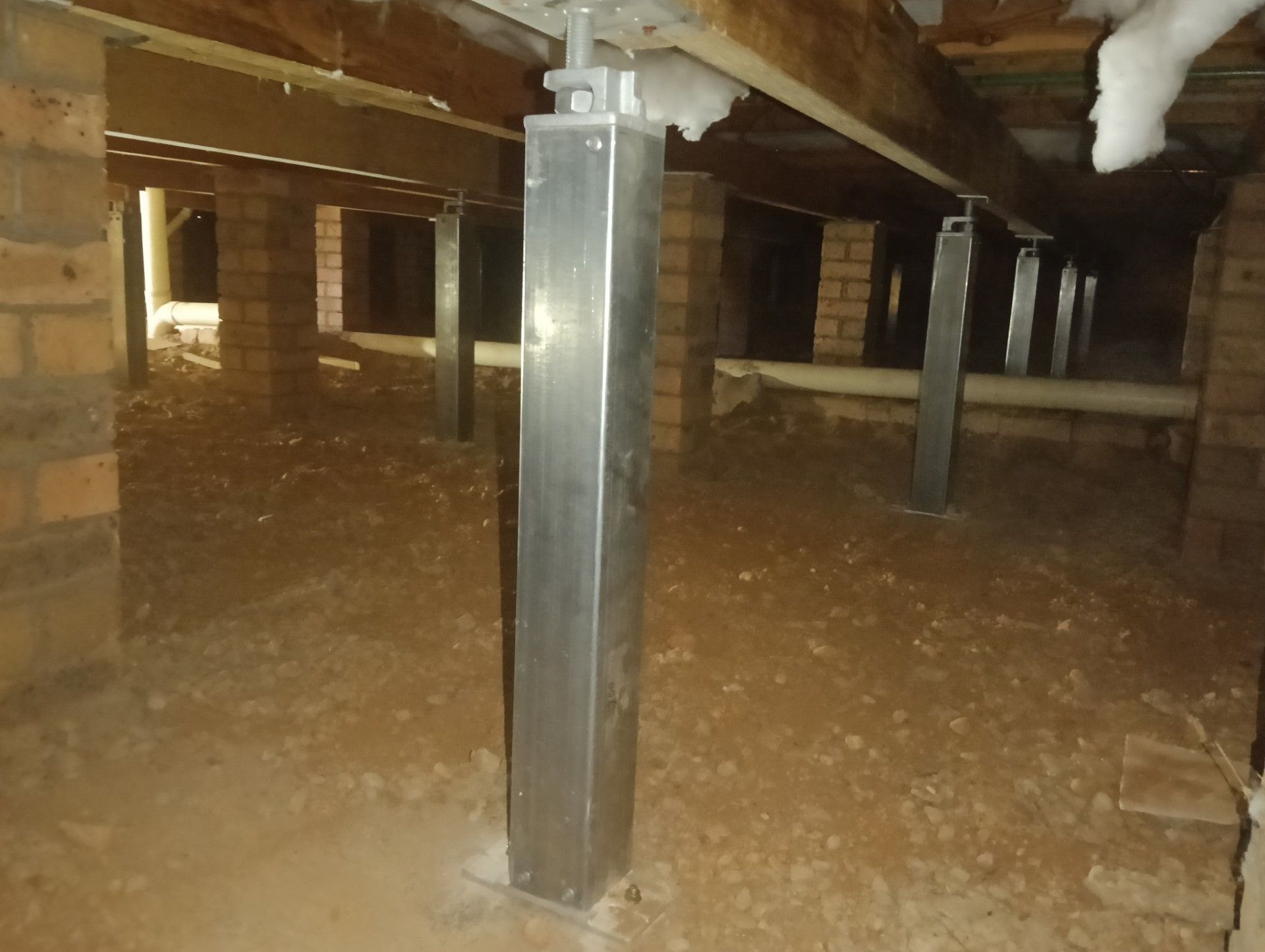 House lifted on jacks over dug-out foundation trenches and soil piles