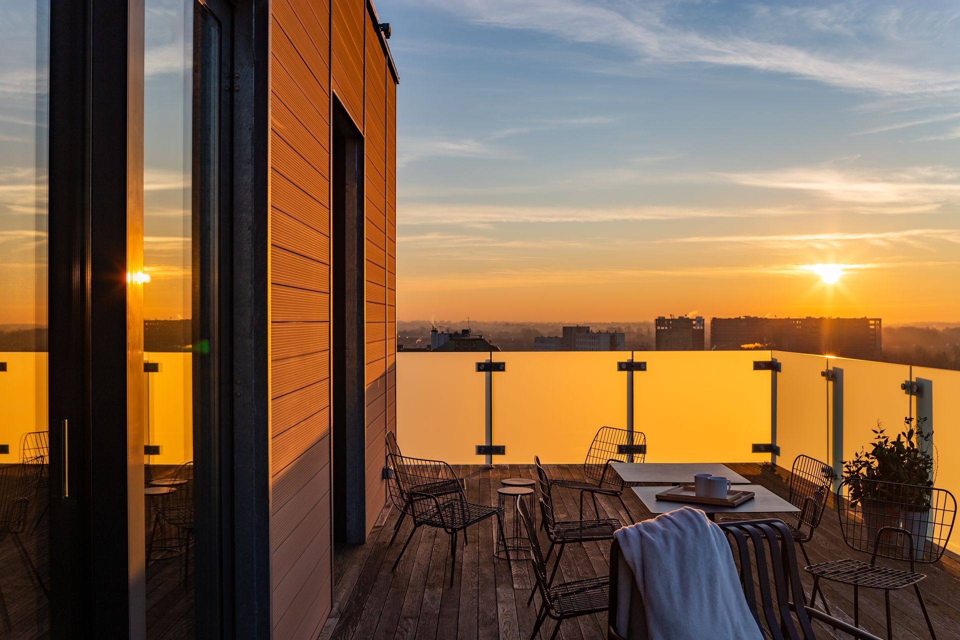 Patio sul tetto con vista sul tramonto. L'arredamento include sedie, tavolo e un asciugamano.