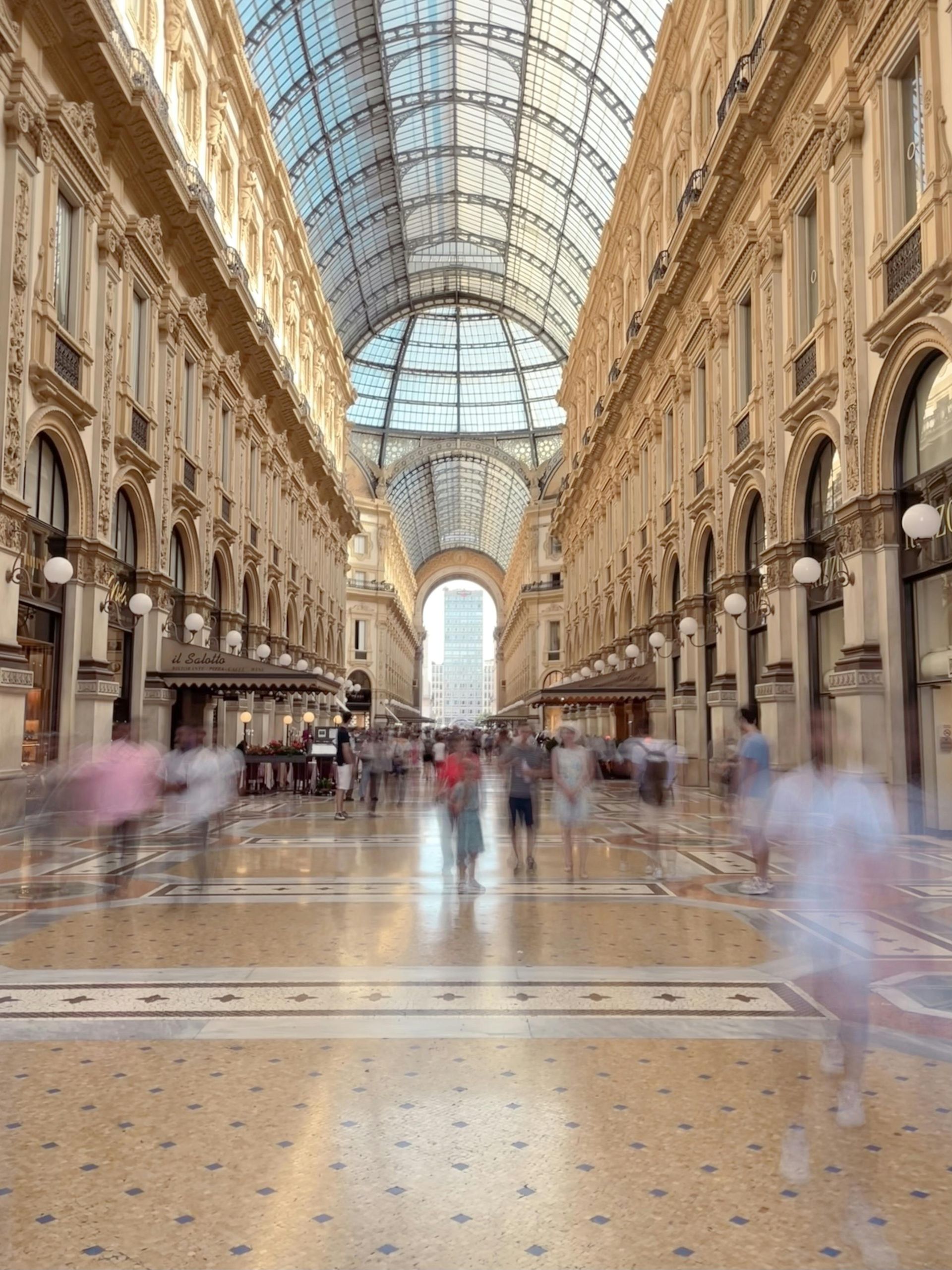 Galleria commerciale con soffitto in vetro, animata da un traffico pedonale confuso.