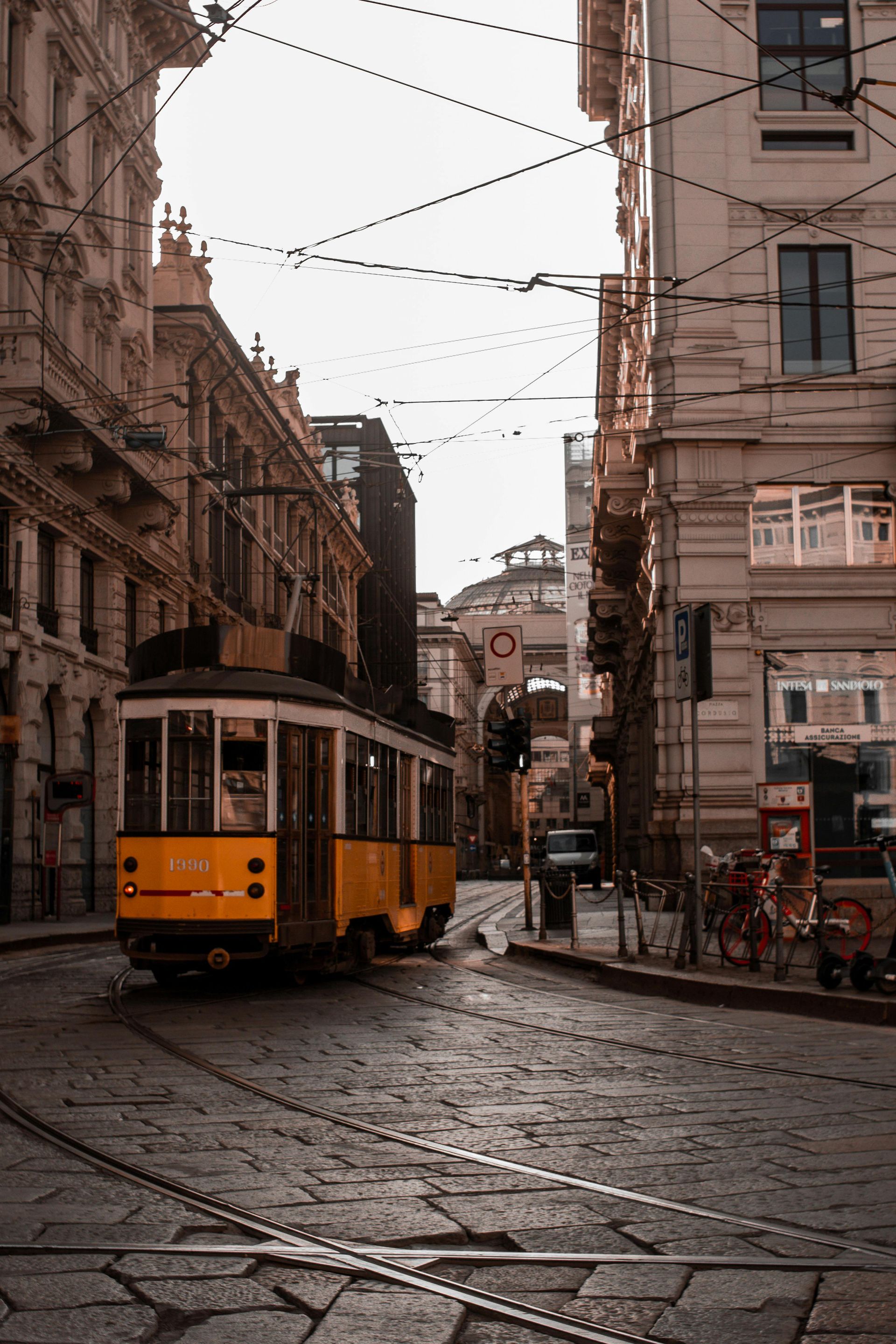 Tram giallo su una strada acciottolata in una città europea. Edifici lungo la strada.