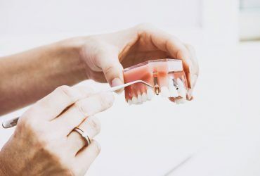 Hands adjusting eyeglasses with a small screwdriver on a white table