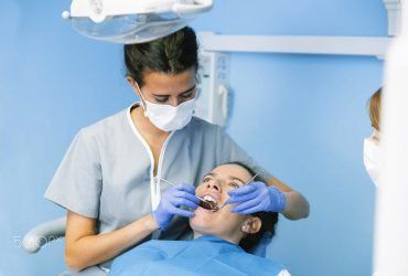 Dentist in mask and gloves examining a patient during a dental checkup