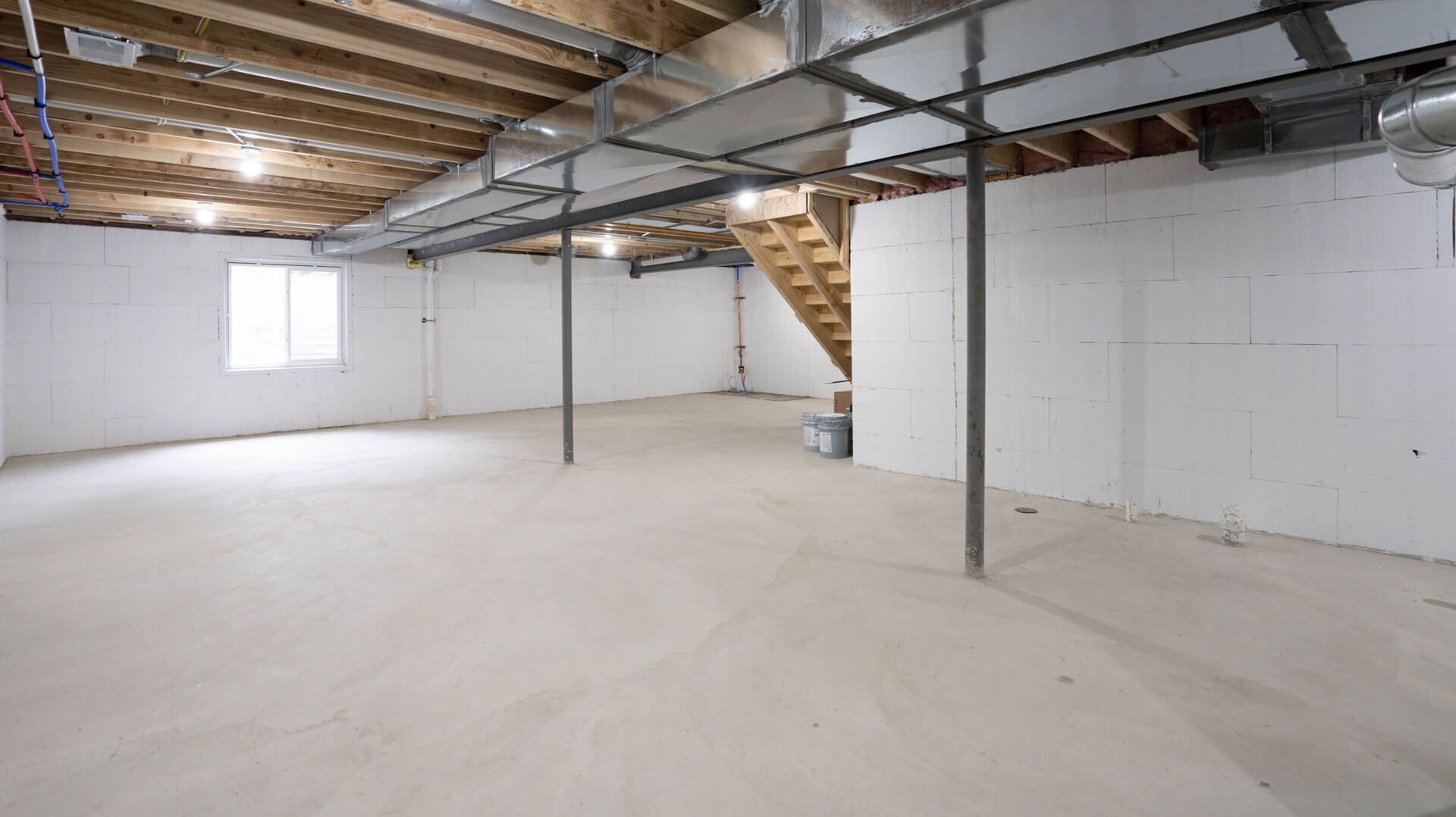 An empty basement with white walls and a staircase.