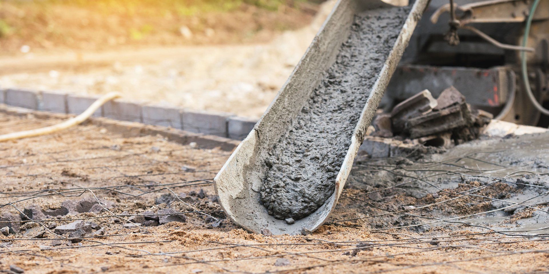 A concrete mixer is pouring concrete into a bucket on a construction site.