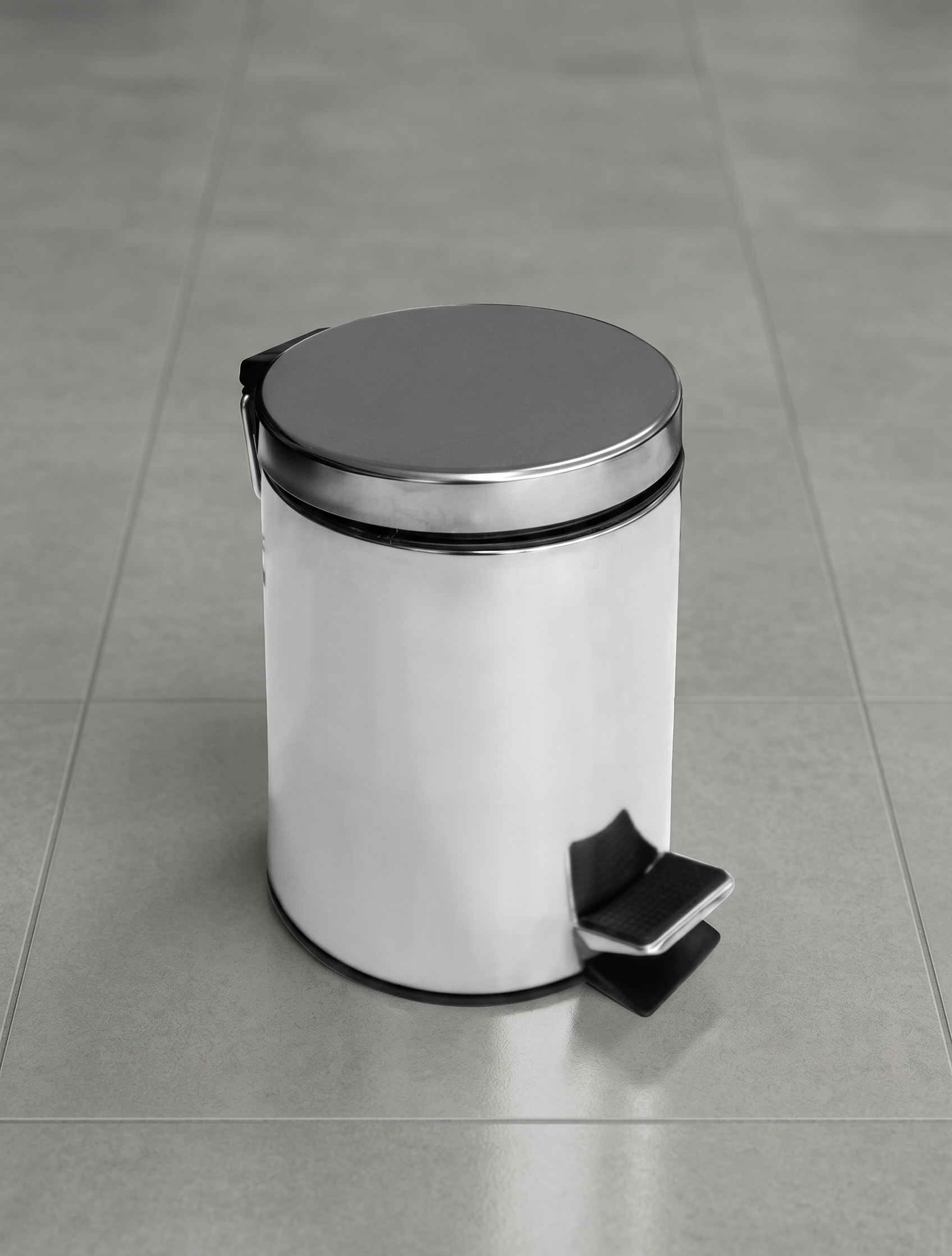 White pedal trash can with a silver lid on a gray tiled floor