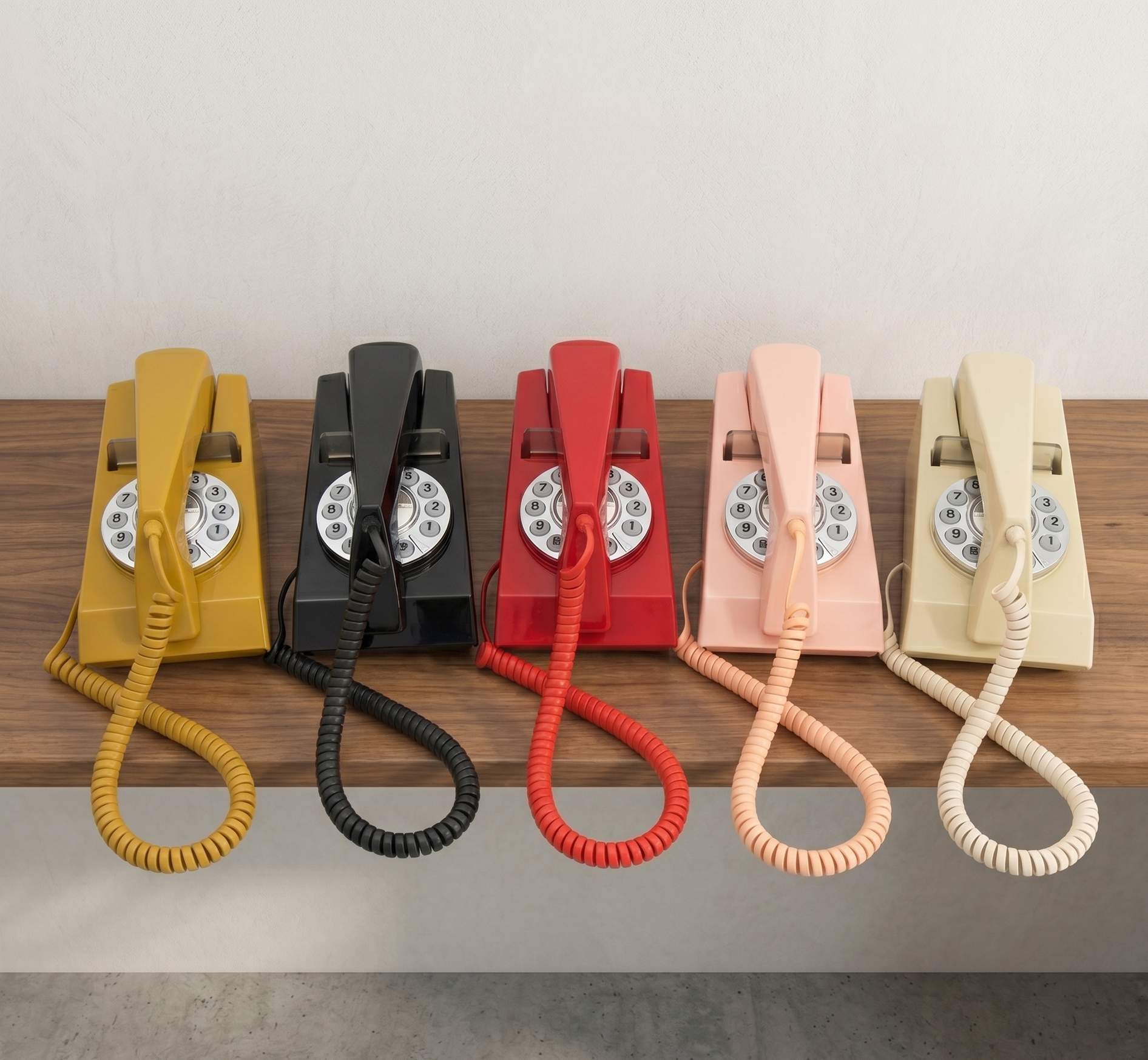 Row of five retro telephones in mustard, black, red, pink, and cream on a shelf