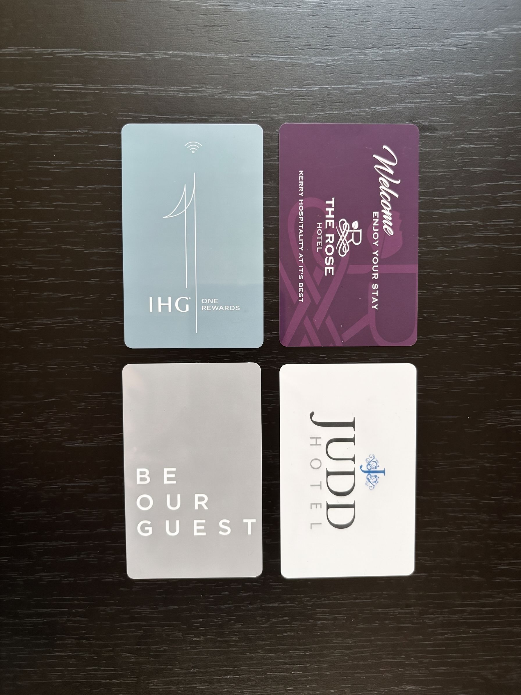Four hotel key cards on a dark table, arranged in a 2x2 grid.