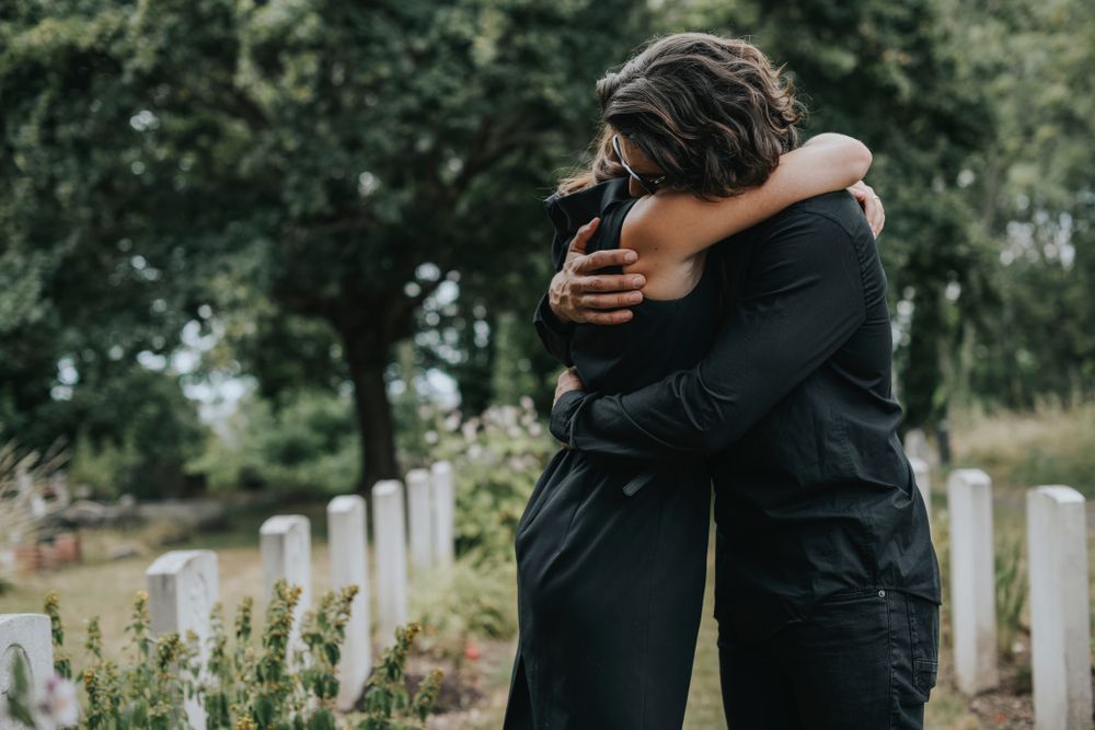 Two People In Black Clothes Hugging In A Cemetery — Craig Stevens Photography in Pearl Beach, NSW