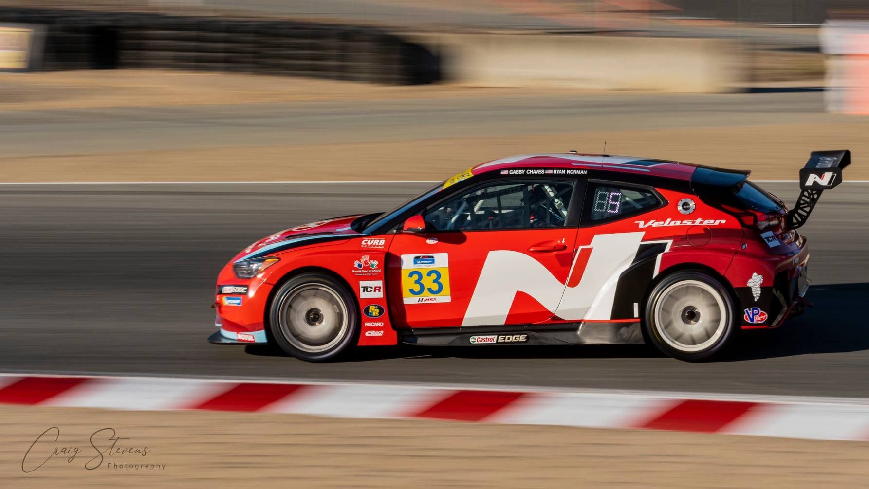 Red Race Car Speeding on a Track, Blurred Background and Striped Curb — Craig Stevens Photography in Sydney, NSW