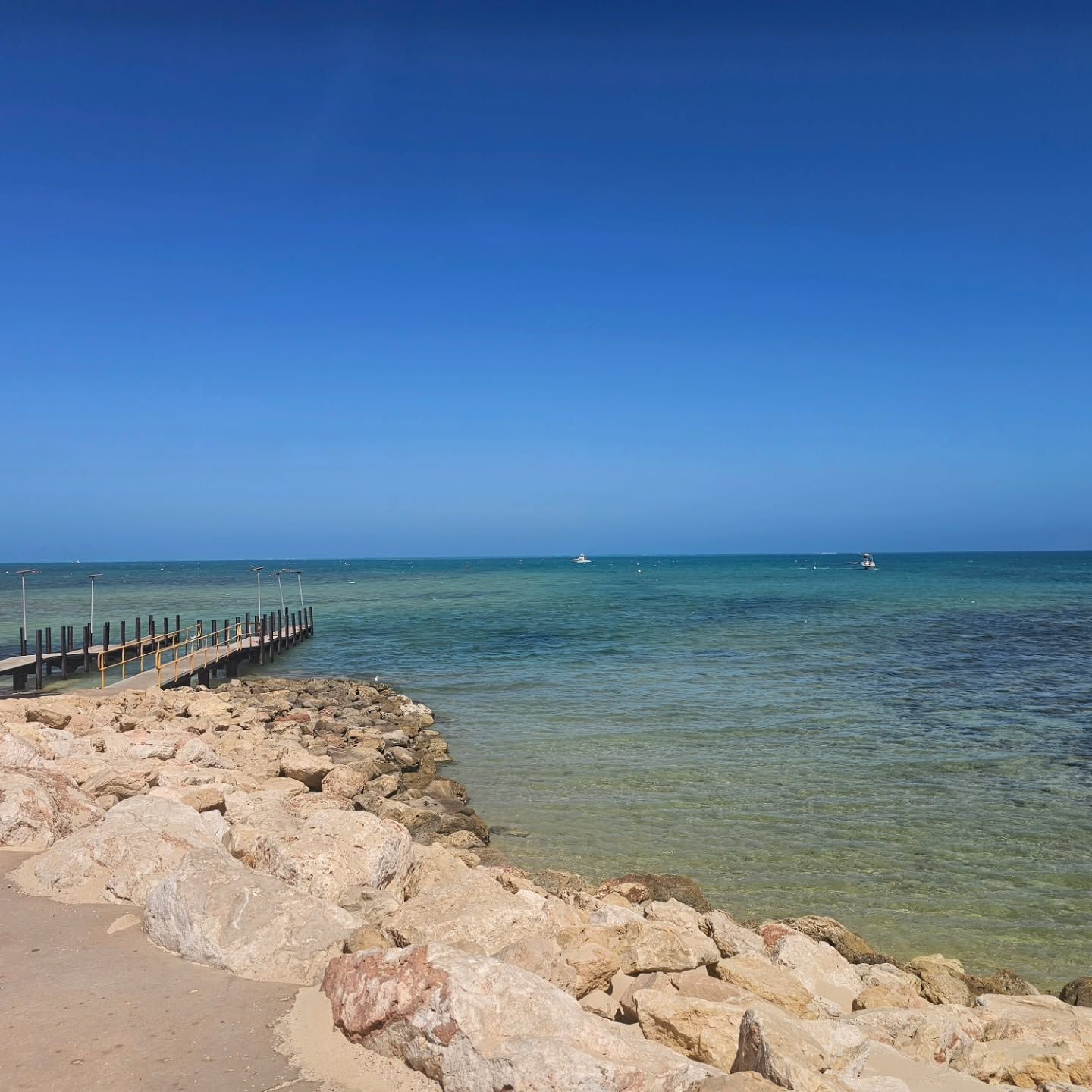 Rocky Shoreline with Calm Turquoise Sea, Wooden Pier, and Clear Blue Sky — Craig Stevens Photography in Pearl Beach, NSW