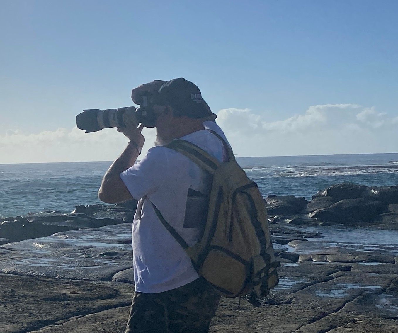 Photographer Holding A Camera At A Rocky Seaside Under A Blue Sky — Craig Stevens Photography in Pearl Beach, NSW