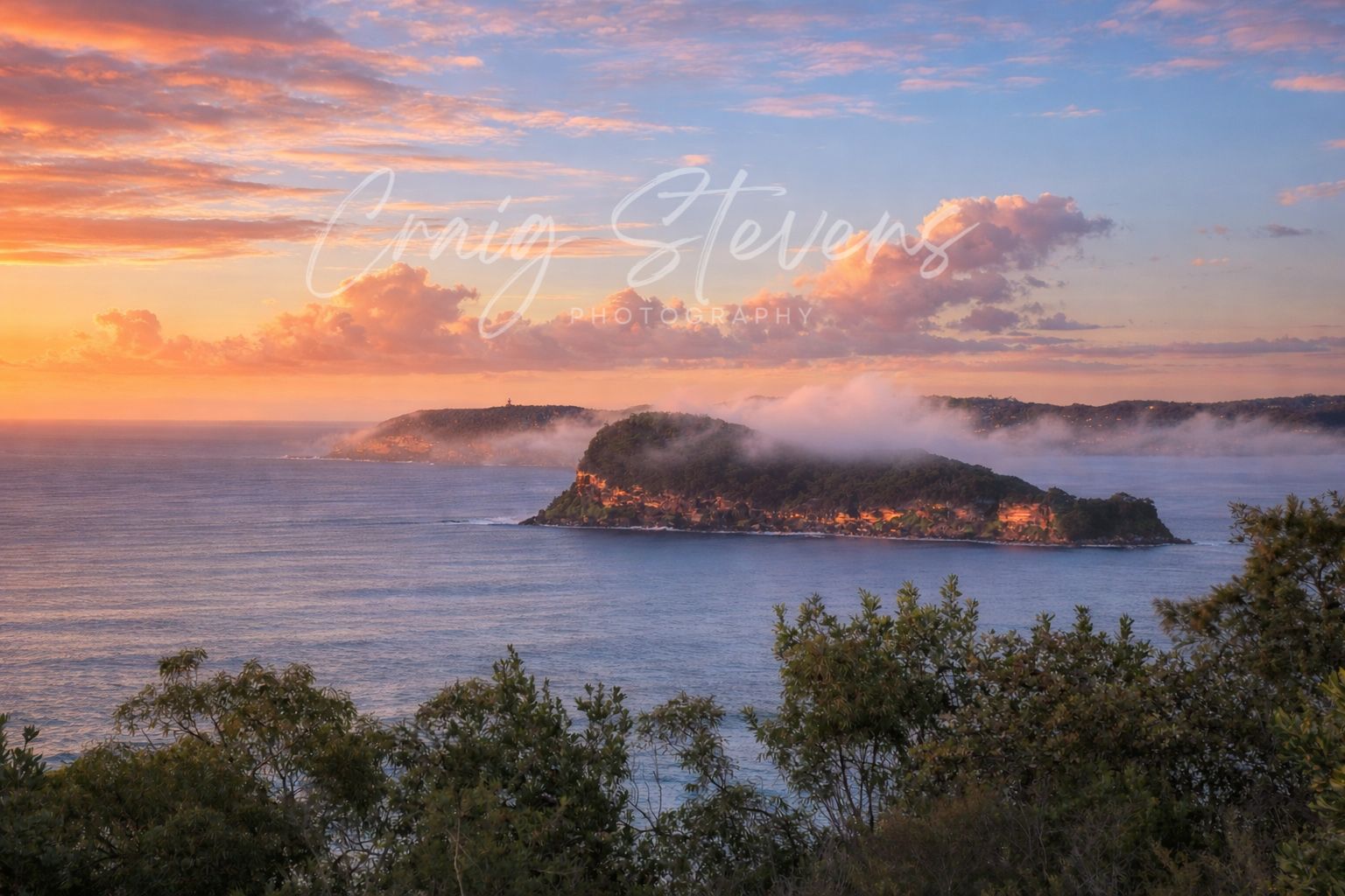 Sunrise Over a Foggy Coastline with A Rocky Island and Calm Ocean Under Pink Orange Clouds — Craig Stevens Photography in Pearl Beach, NSW