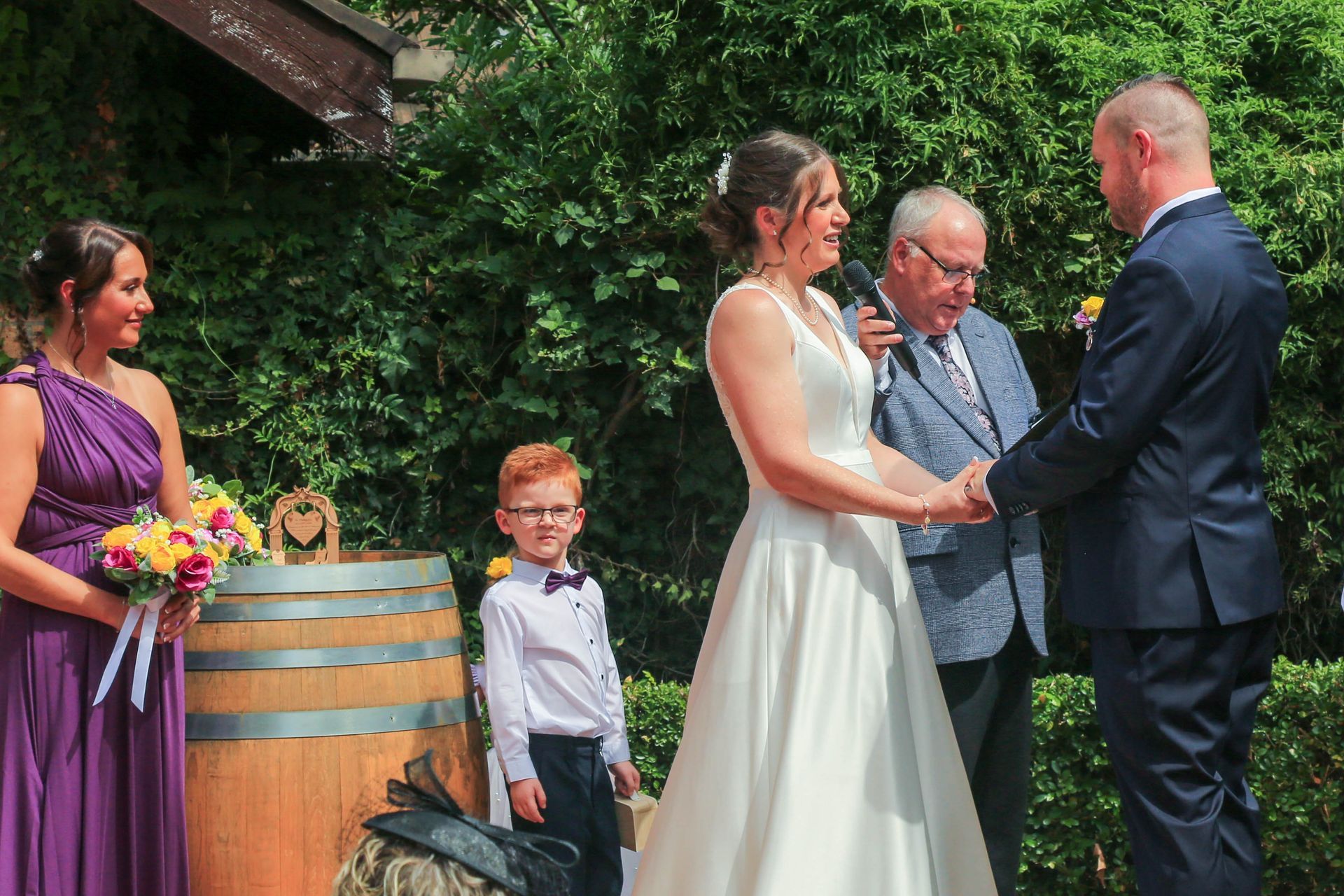 Wedding Ceremony Outdoors with Bride and Groom Exchanging Vows Beside an Officiant and A Child on The Left — Craig Stevens Photography in Pearl Beach, NSW