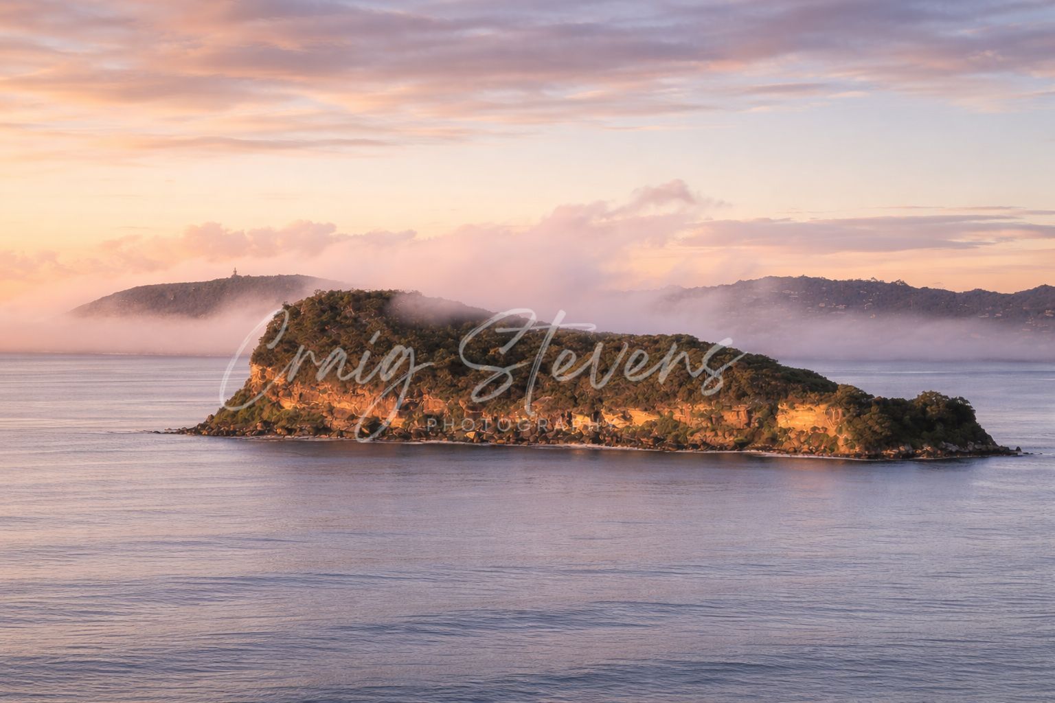 Sunlit Rocky Island with Pink Sky and Calm Water, Overlaid with Craig Stevens Text — Craig Stevens Photography in Pearl Beach, NSW