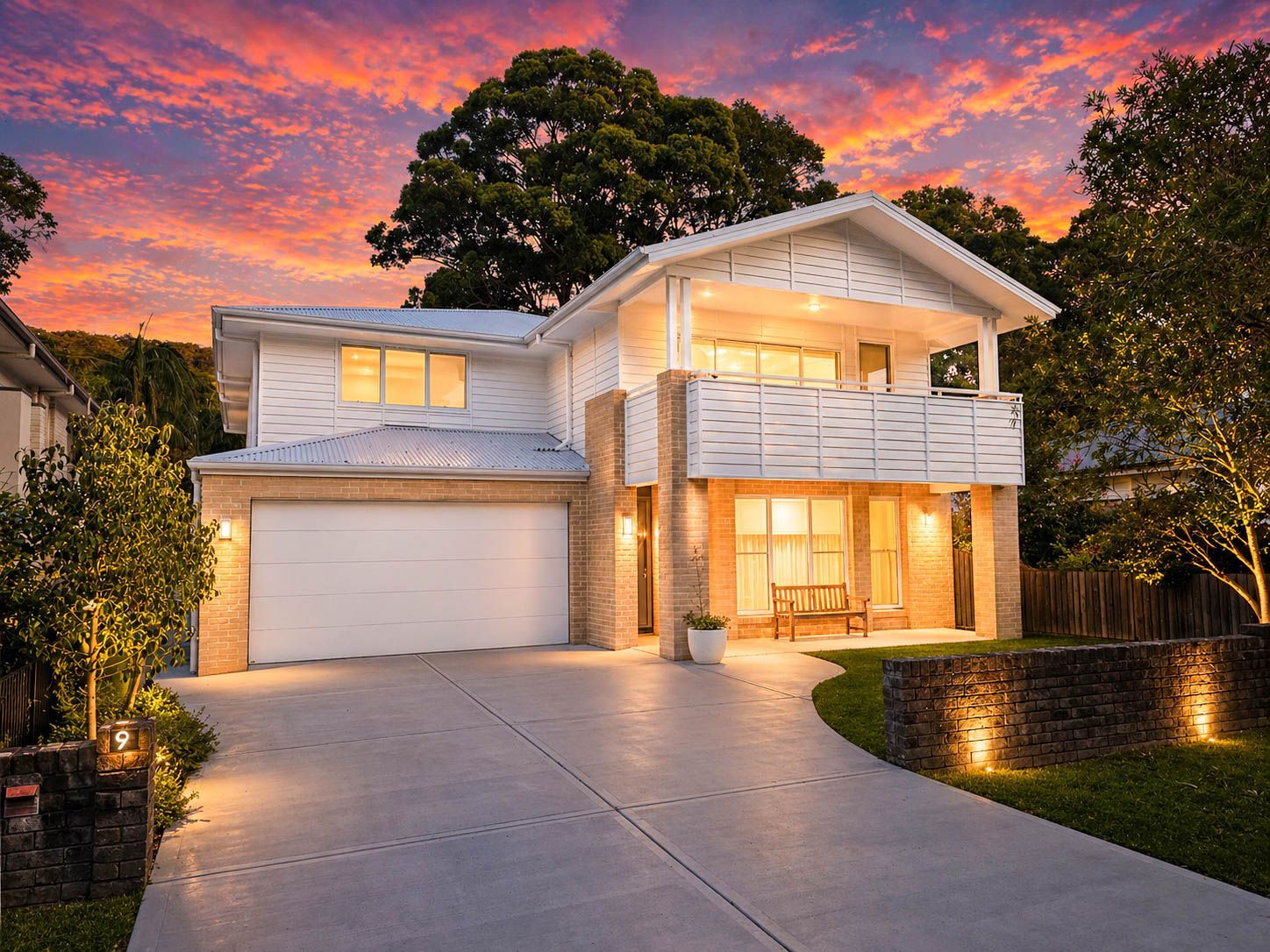 Modern two-story house with lit windows and garage at sunset under a vivid orange sky  - Craig Stevens Photography in Pearl Beach, NSW
