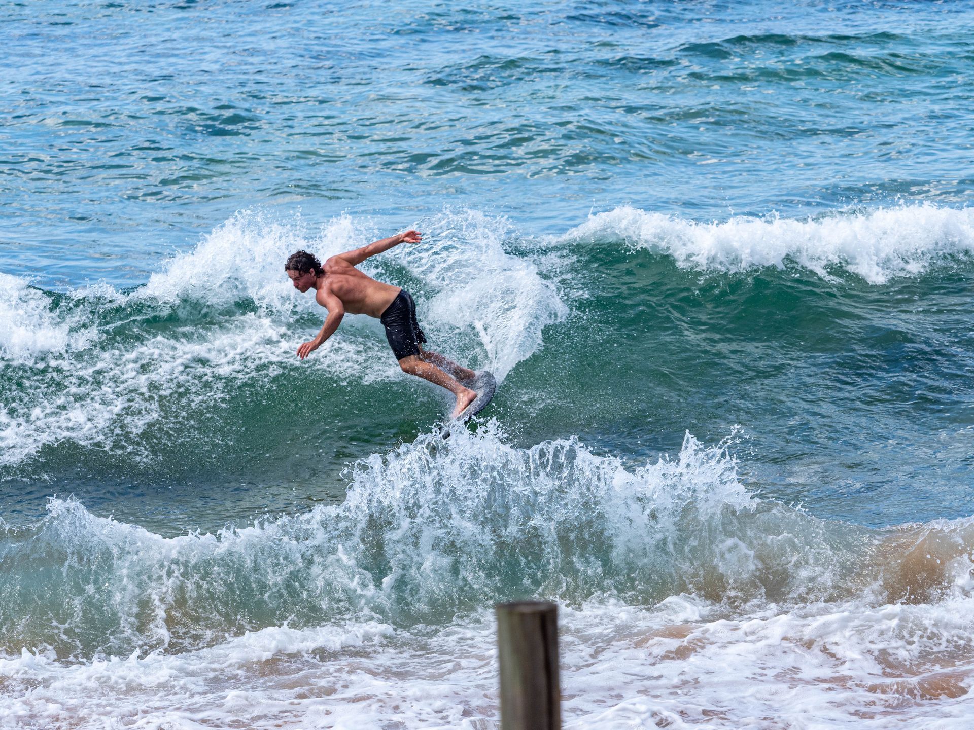 Surfer In Black Shorts Riding A Wave Near The Shore — Craig Stevens Photography in Pearl Beach, NSW