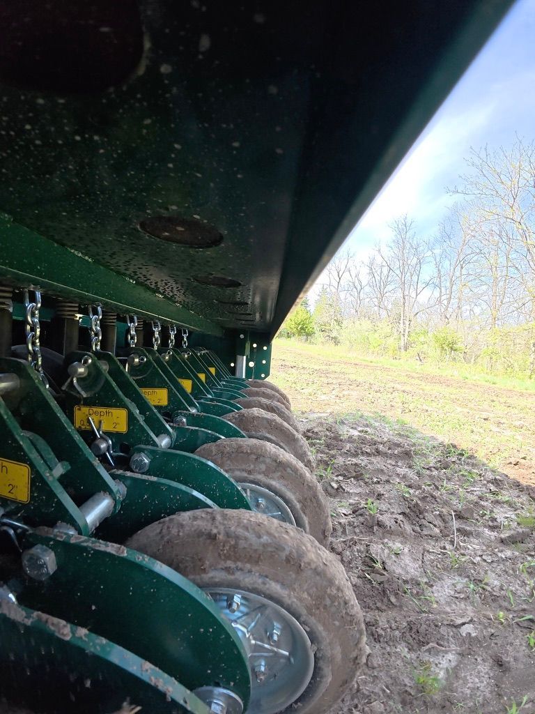 Close-up of row crop planter wheels in a muddy field, viewed from beneath the machine