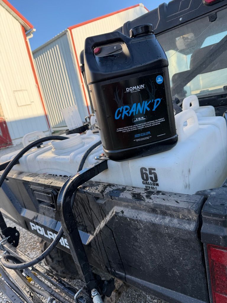 Black bottle labeled “CRANK” on a white cooler beside a pickup truck in snowy outdoor setting