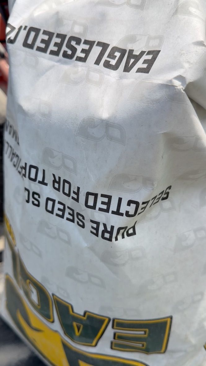 Crumpled white EAGLE seed bag with black and yellow text, photographed close up.