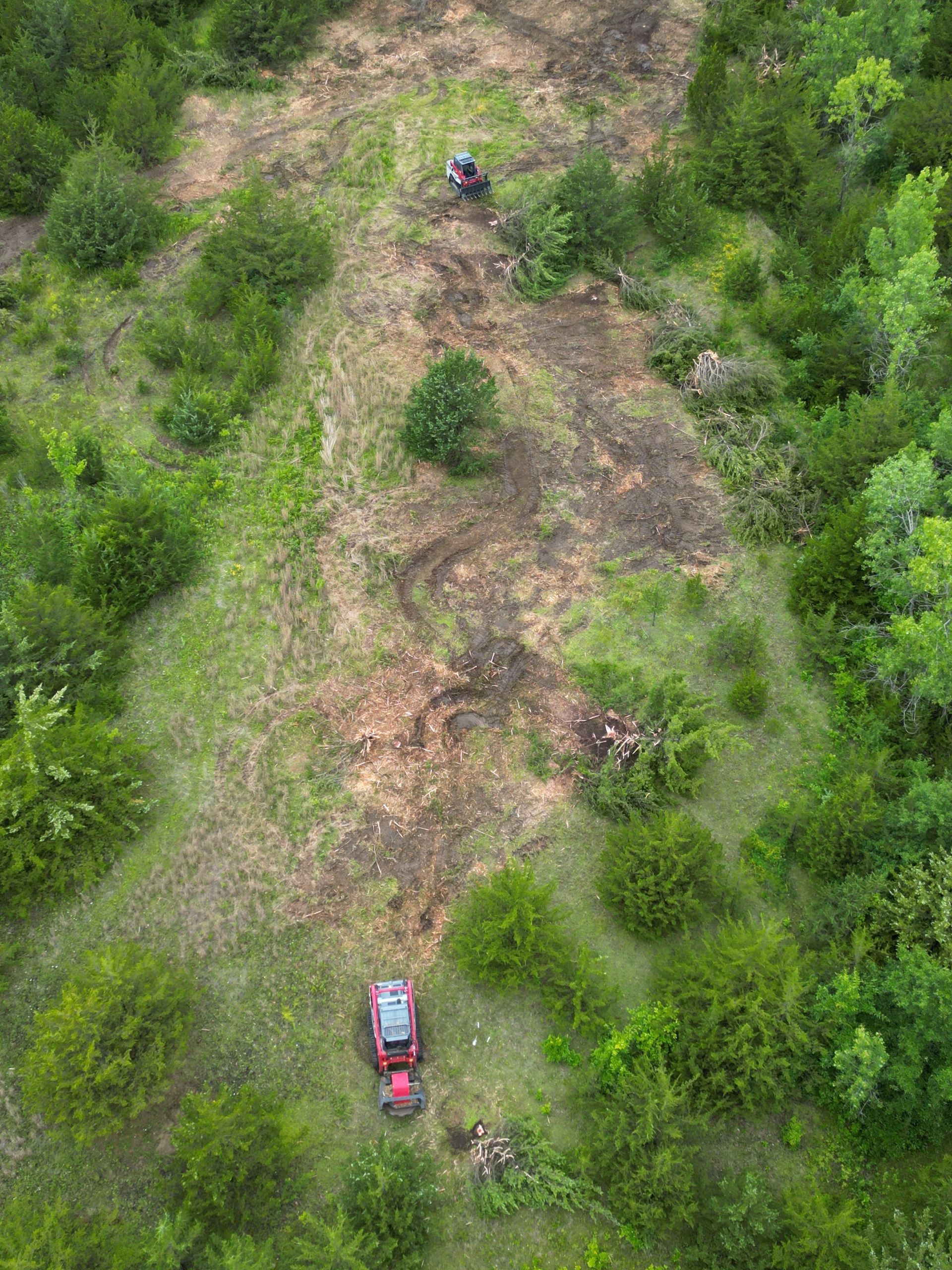 Aerial view of a green field with a large tan patch of bare soil and surrounding hedgerows.