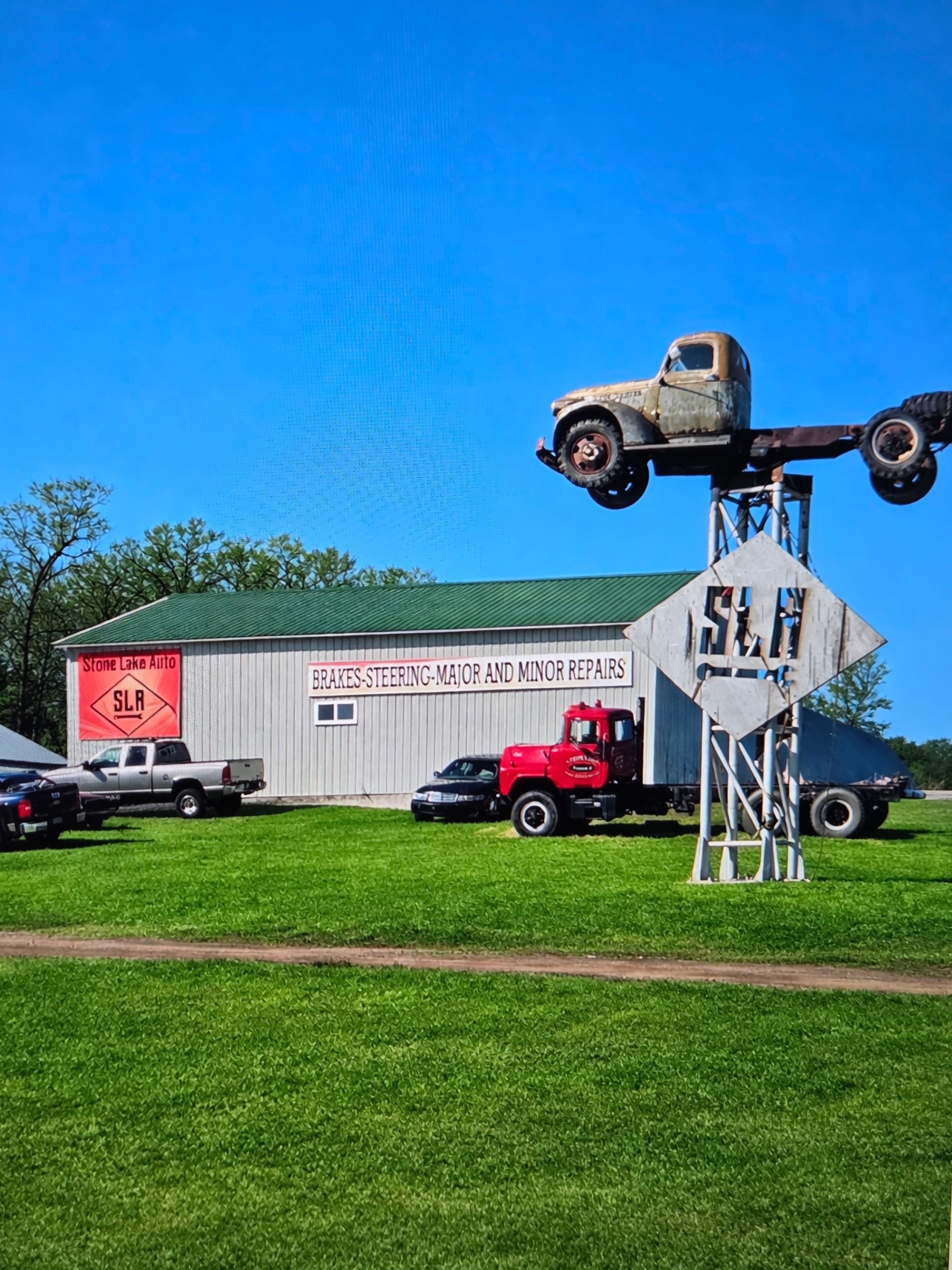 Vintage truck sculpture on a pole outside a white building | Stone Lake Auto
