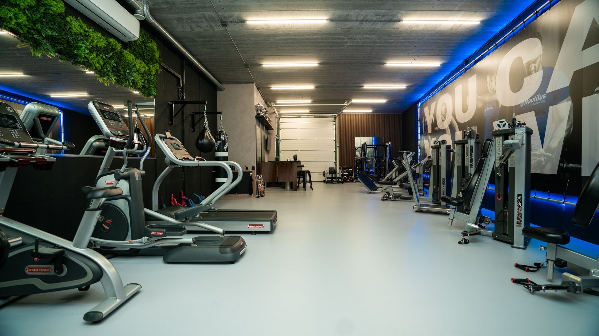 Modern fitnesscentrum met loopbanden, gewichtsapparaten en blauwe accentverlichting.