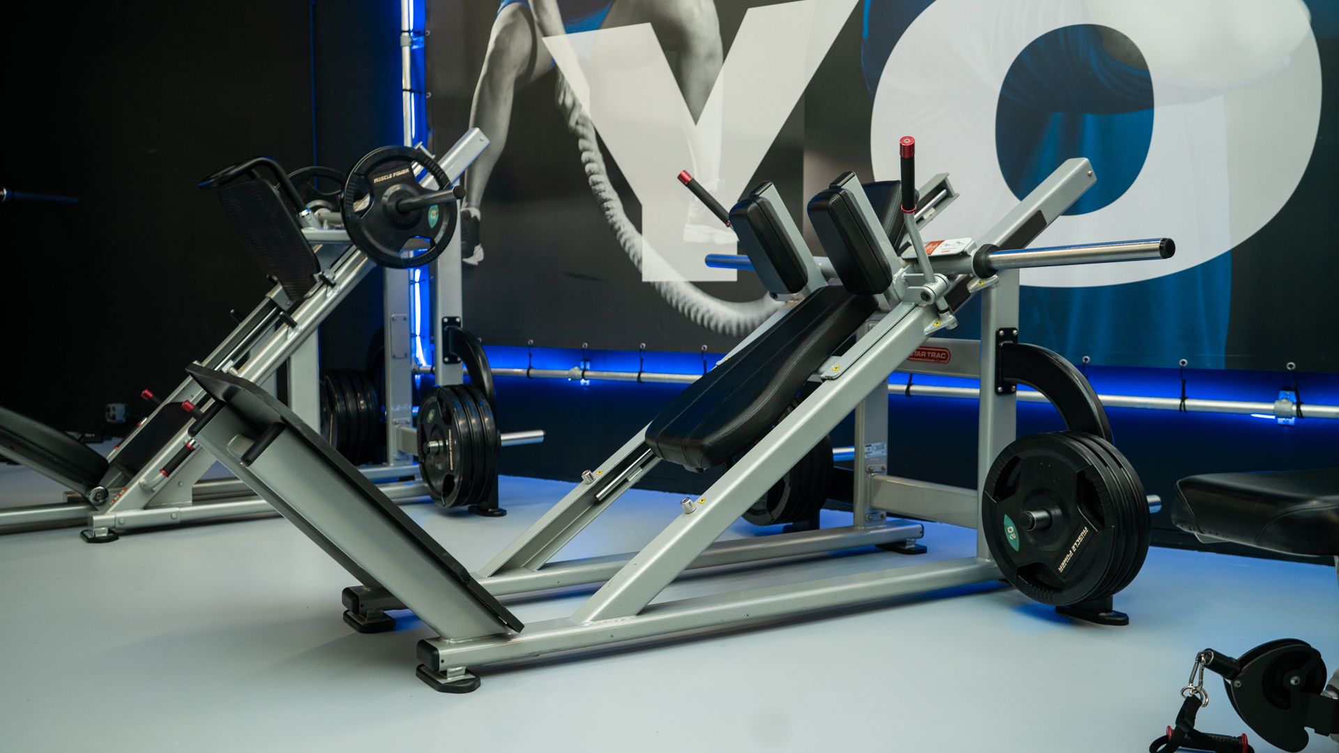 Modern fitnessapparaat met zilverkleurig frame en zwarte wielen, verlicht door blauwe accenten.