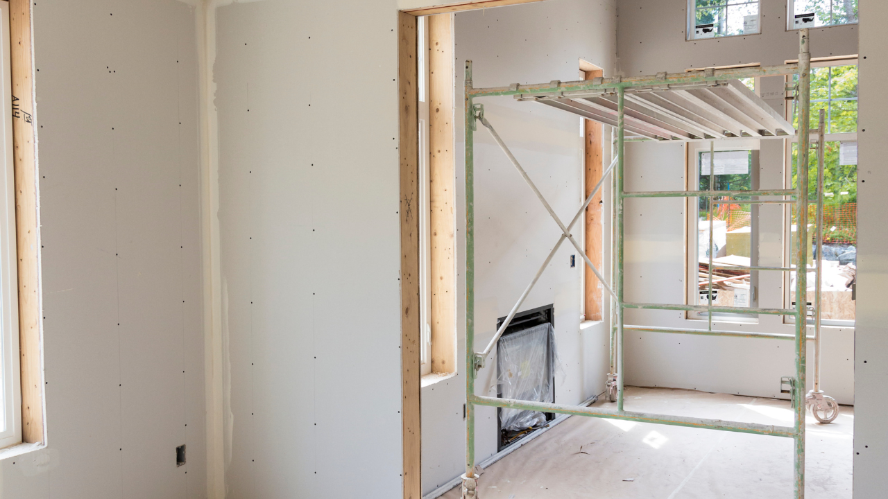 Interior of a room under construction with drywall and a scaffolding.