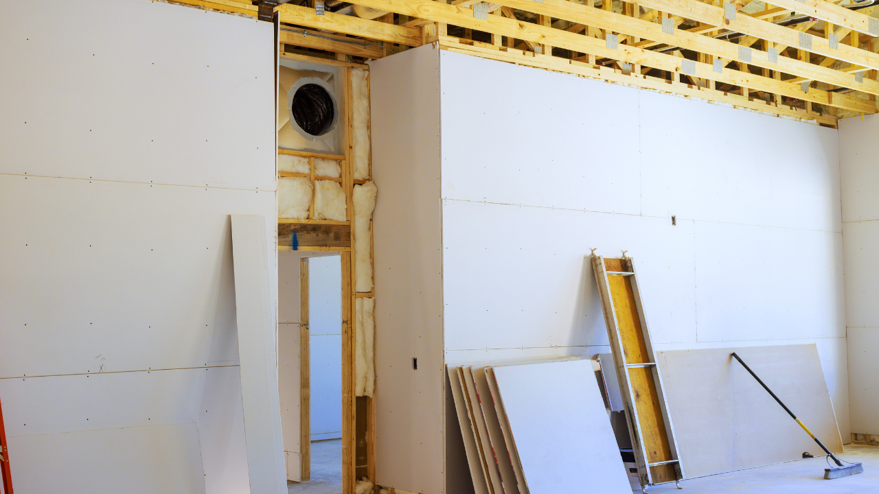 Interior room under construction, drywall partially installed; exposed wood framing and ventilation visible.